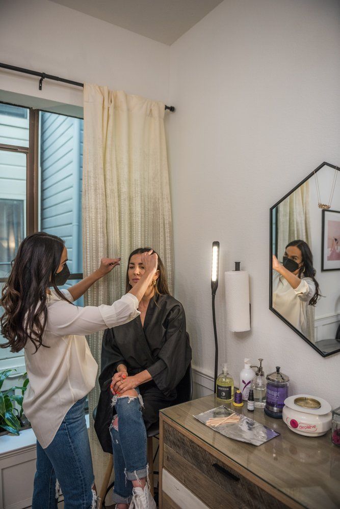 A woman is getting her makeup done by a makeup artist in a room.