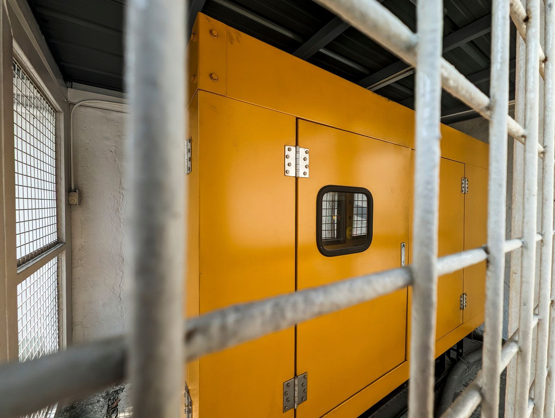 Yellow generator behind metal bars.