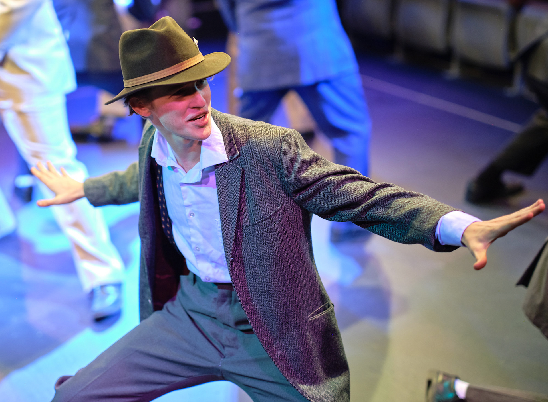 A man in a suit and hat is dancing on a stage