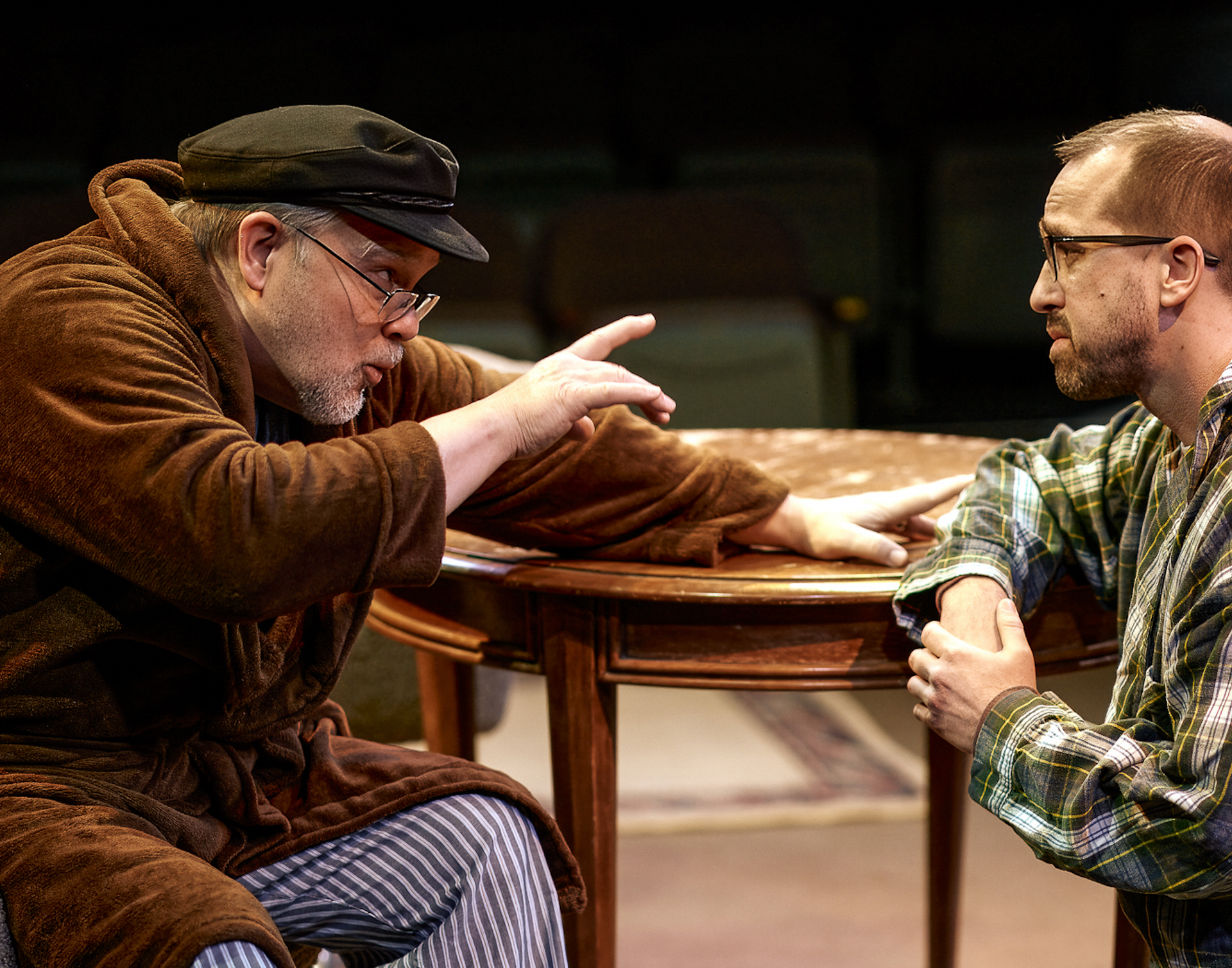 Two men are sitting at a table talking to each other