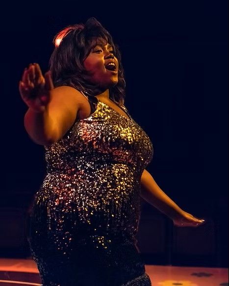 A woman in a sequined dress is singing into a microphone