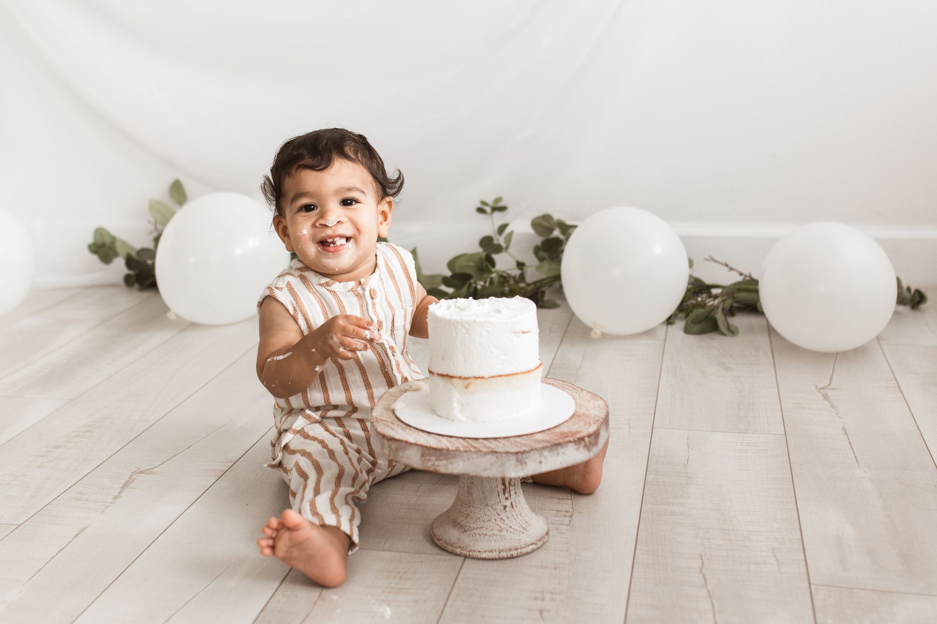 A baby girl is sitting on the floor holding a cake.