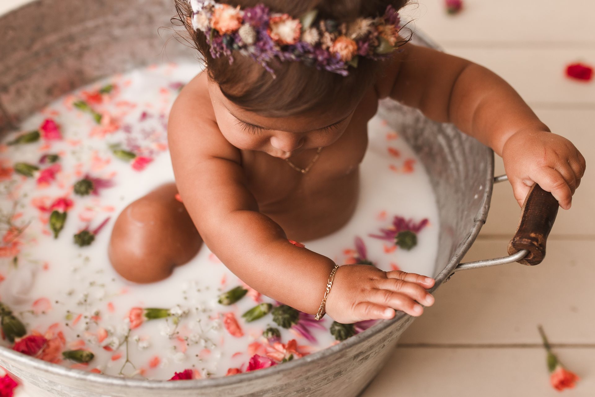 A baby girl is sitting in a small bed.