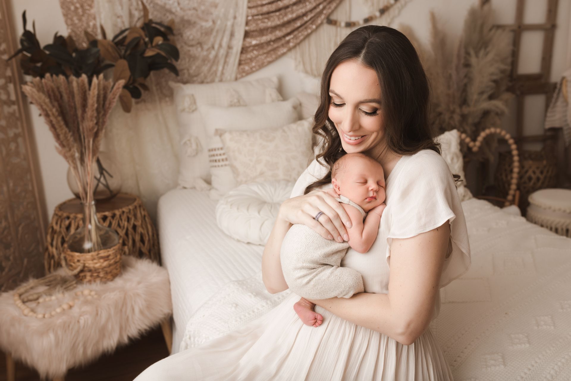 A newborn baby girl wearing a headband is sleeping on a white surface.
