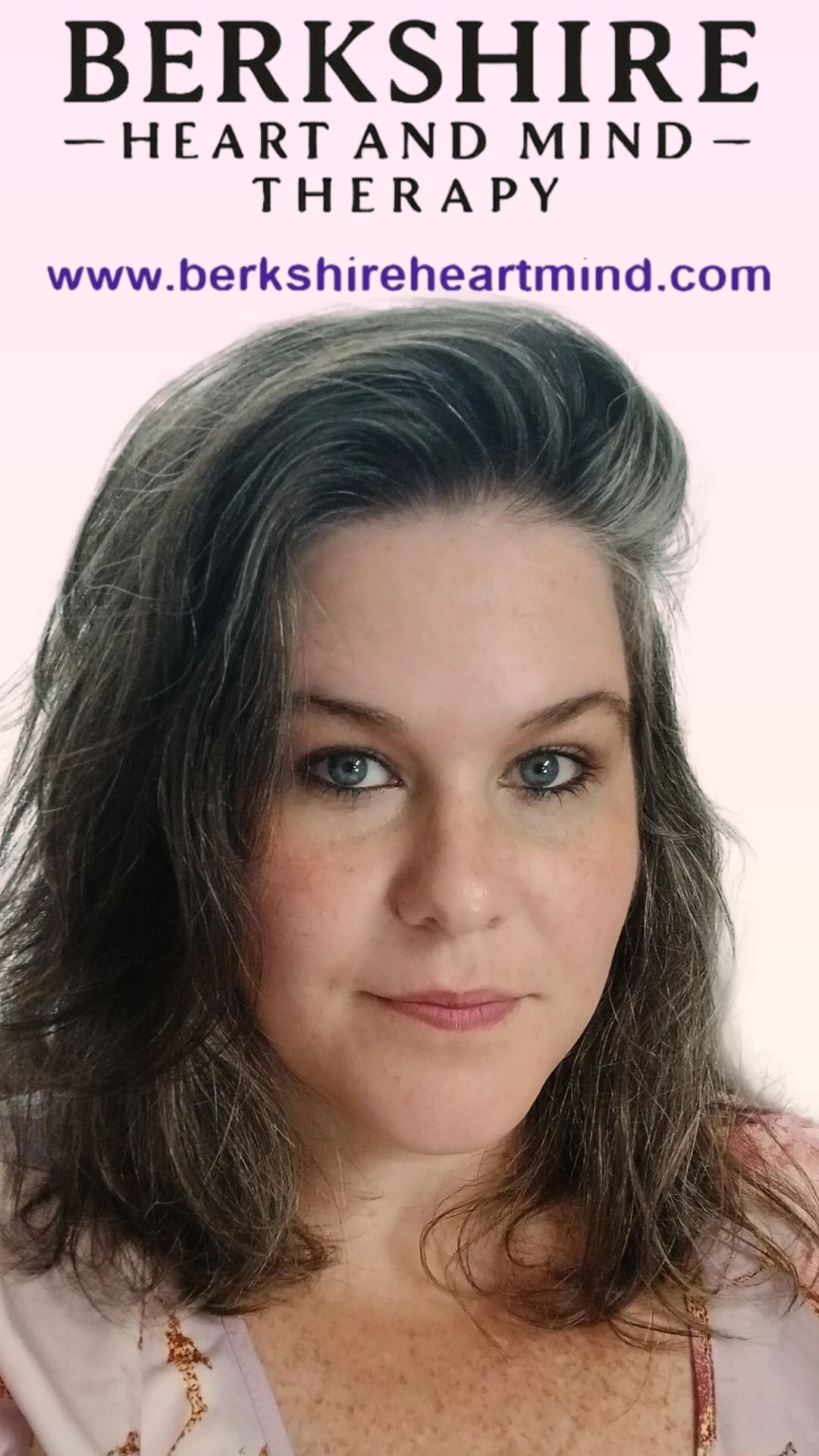 Picture of a woman in a pink shirt sitting in front of a peach background with the company name Berkshire Heart and Mind Therapy behind her.