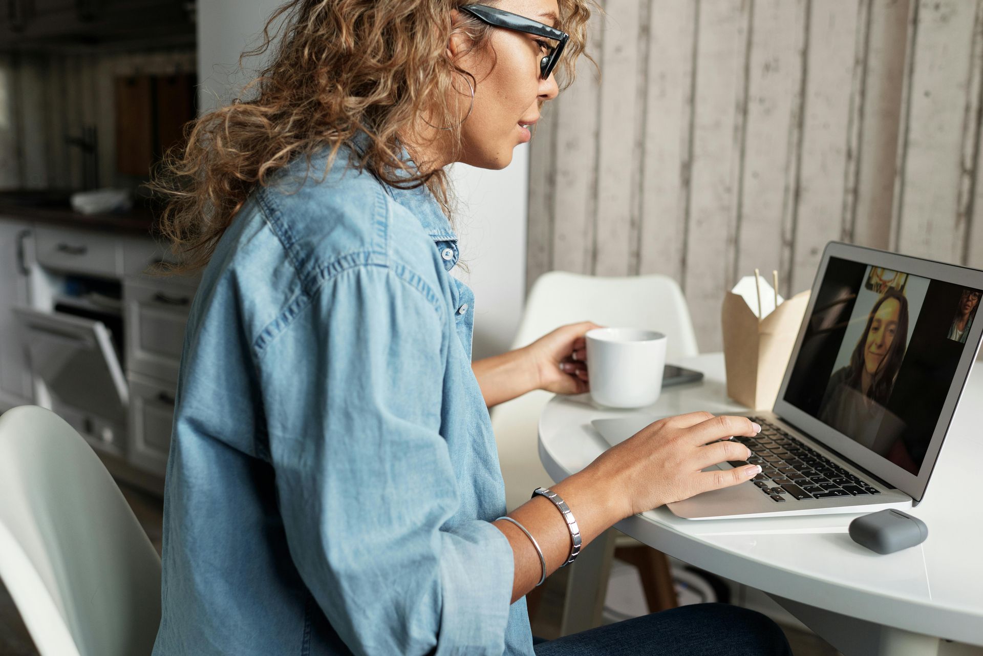 A woman is sitting at a table using a laptop computer.