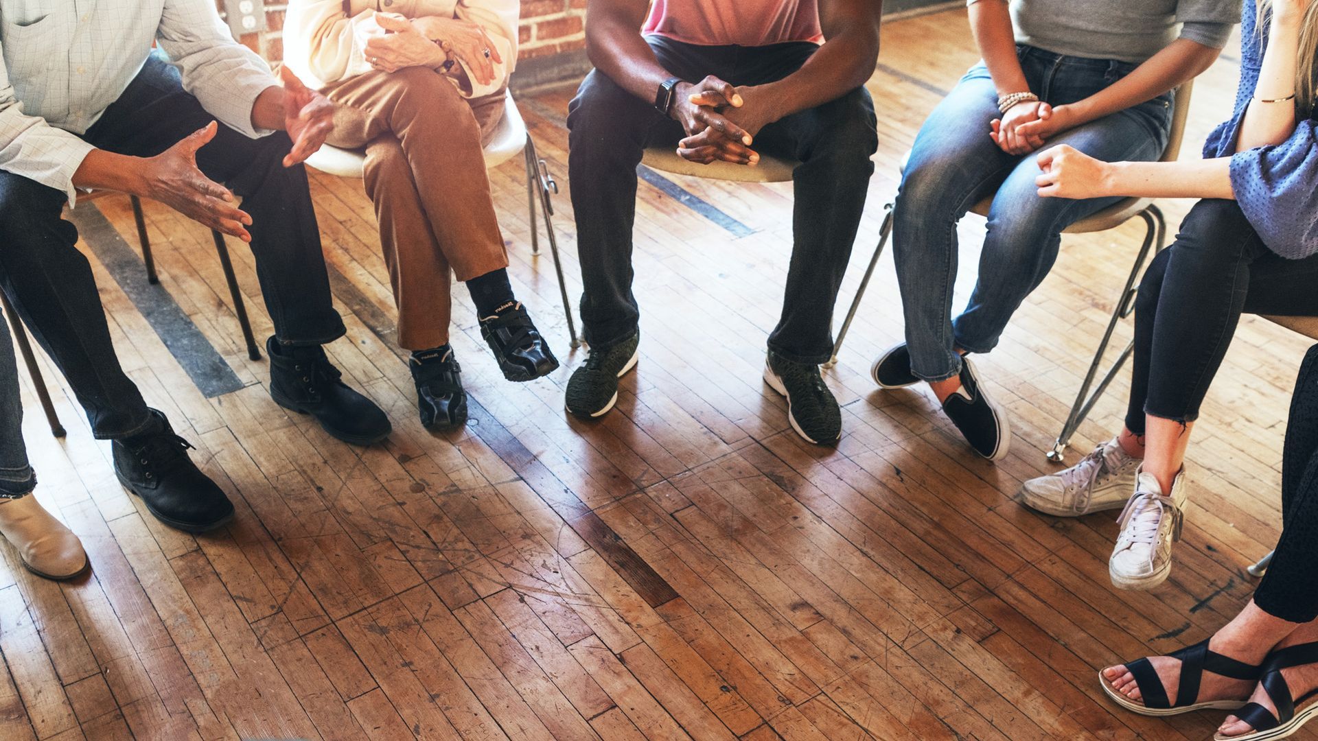 A group of people are sitting in a circle on a wooden floor.
