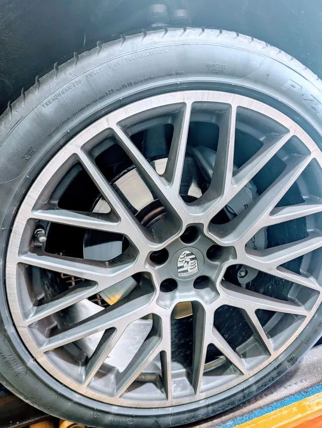 Gray Porsche car wheel with a tire.