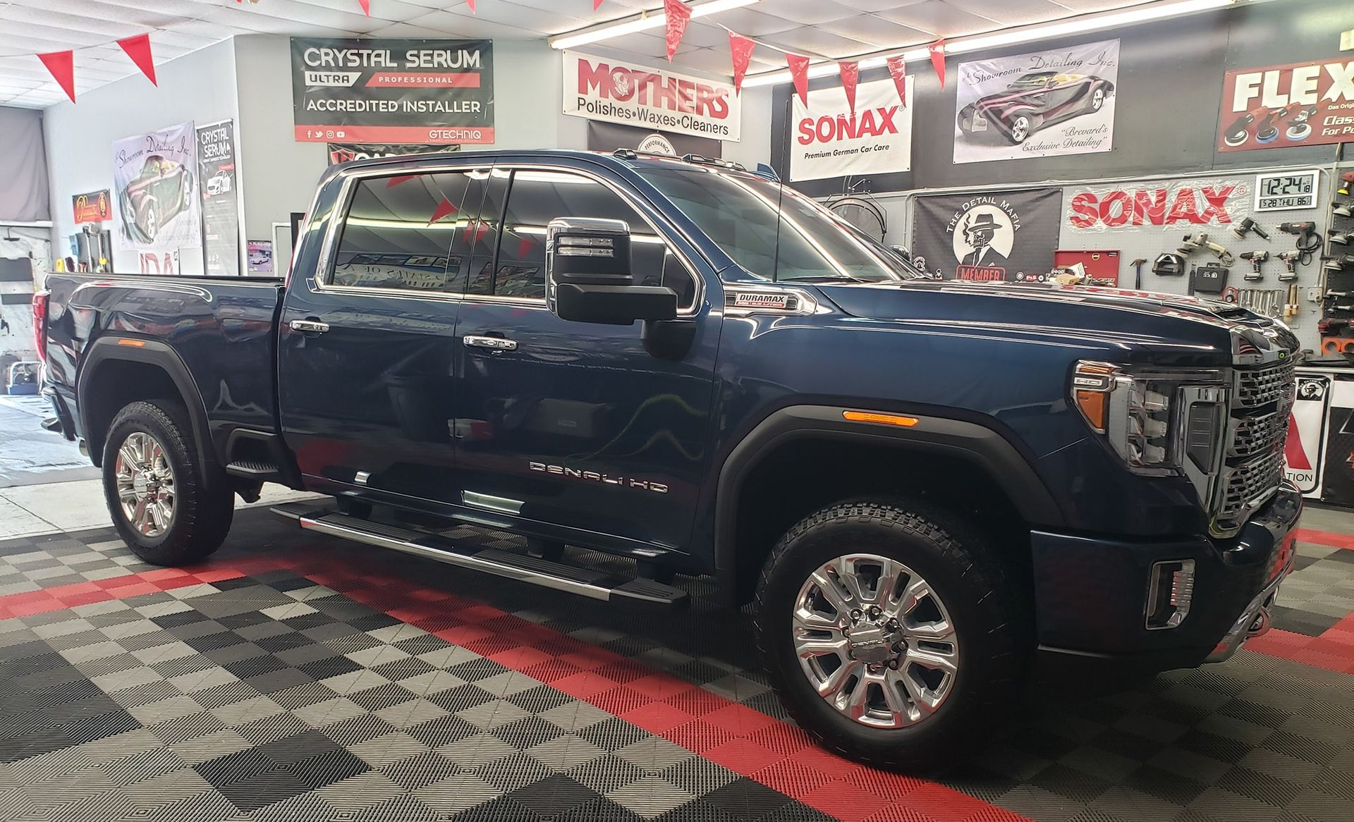 Blue GMC Sierra truck parked inside a shop with checkered floor.