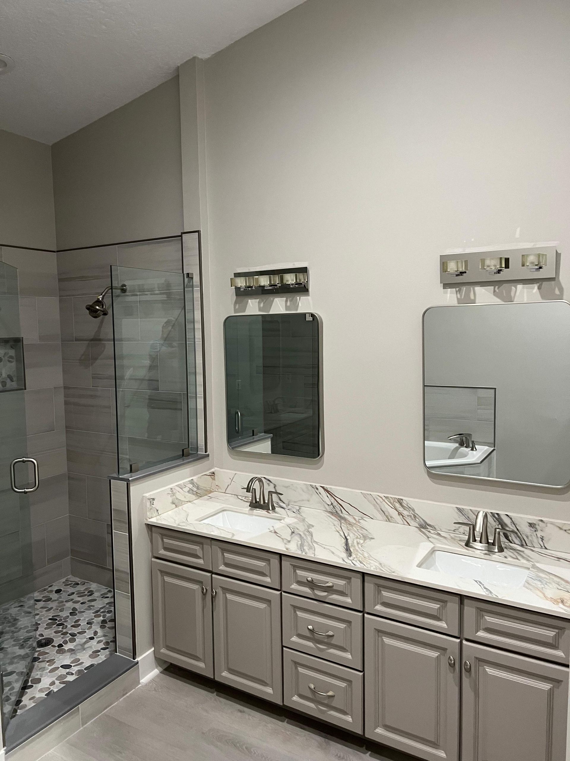 A bathroom with two sinks and a walk in shower.