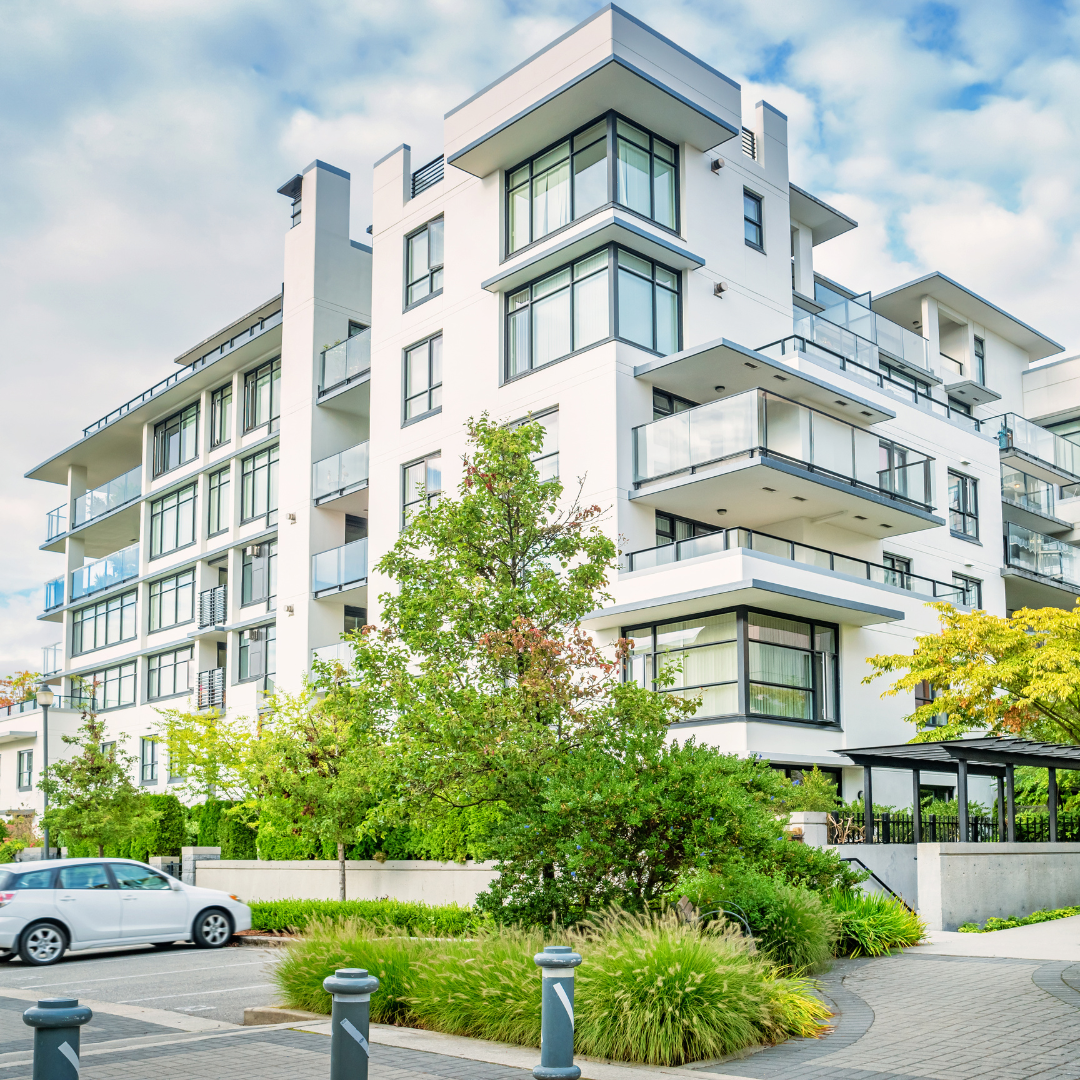 A large white apartment building with a car parked in front of it.