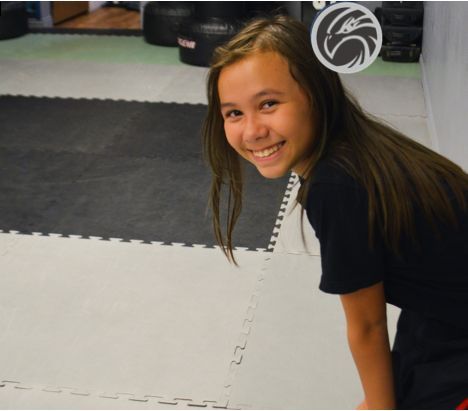 a young girl is smiling while sitting on a mat