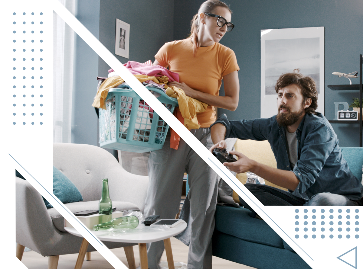 a man is playing a video game while a woman holds a laundry basket .