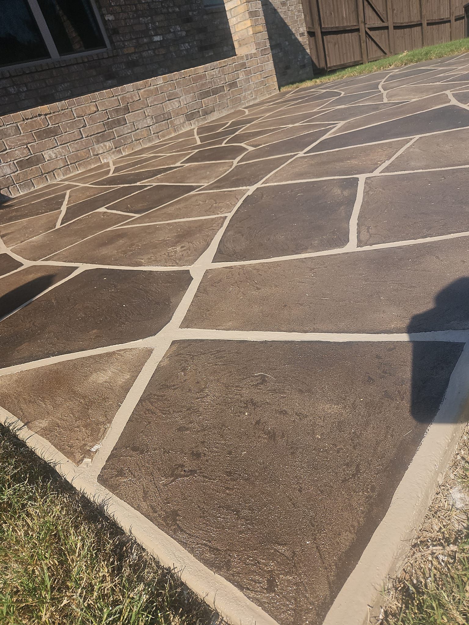 A concrete driveway with a stone wall in the background