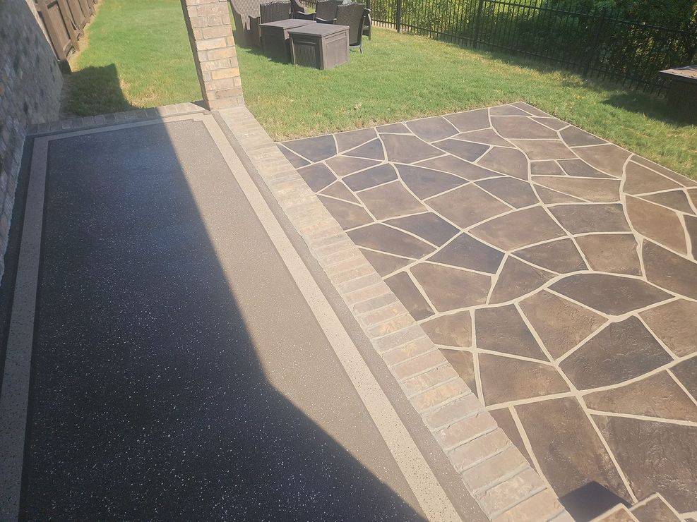 A stone walkway leading to a patio with a table and chairs in the background.