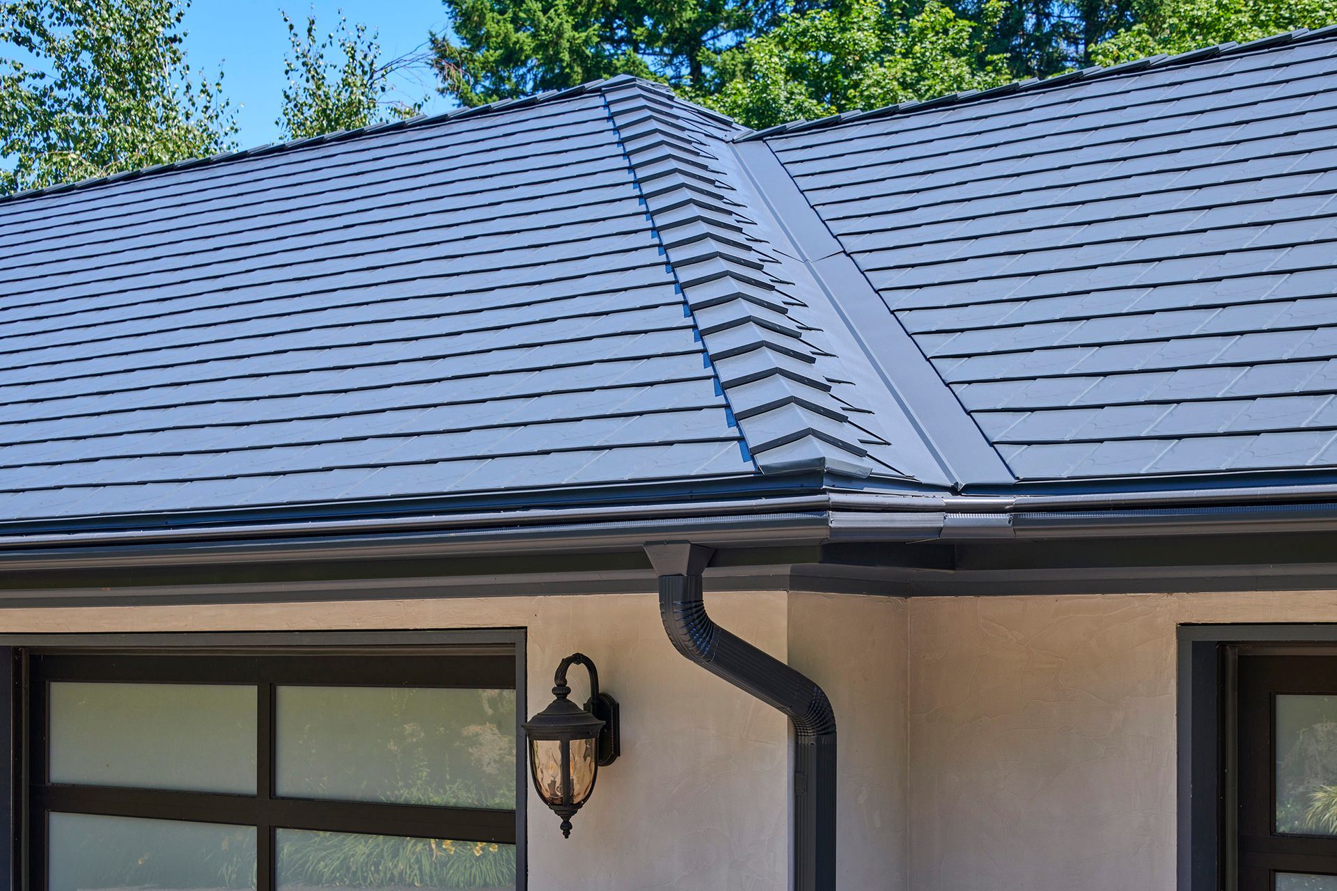 Detailed close-up of the eaves and hip ridges of a Deep Charcoal Interlock Slate aluminum roof in Portland, Oregon. The heavy-gauge aluminum panels are finished with premium coatings for fade resistance and climate durability.