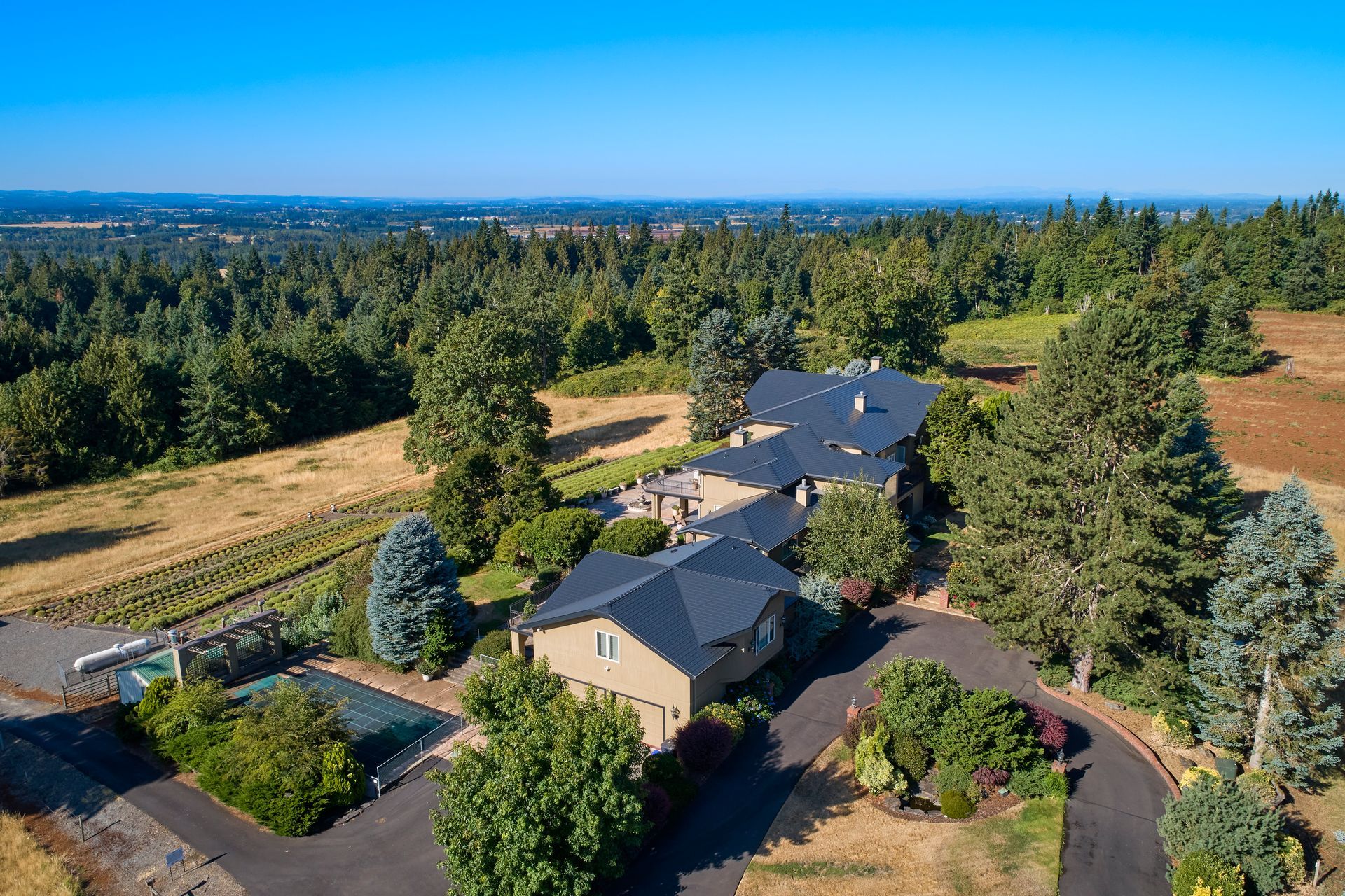Aerial view of a custom home in Mulino, Oregon featuring a premium black Interlock aluminum slate roof installed by Interlock Metal Roofing. The heavy-gauge aluminum roof offers high fire resistance and durability, blending beautifully with the forested Clackamas County landscape.