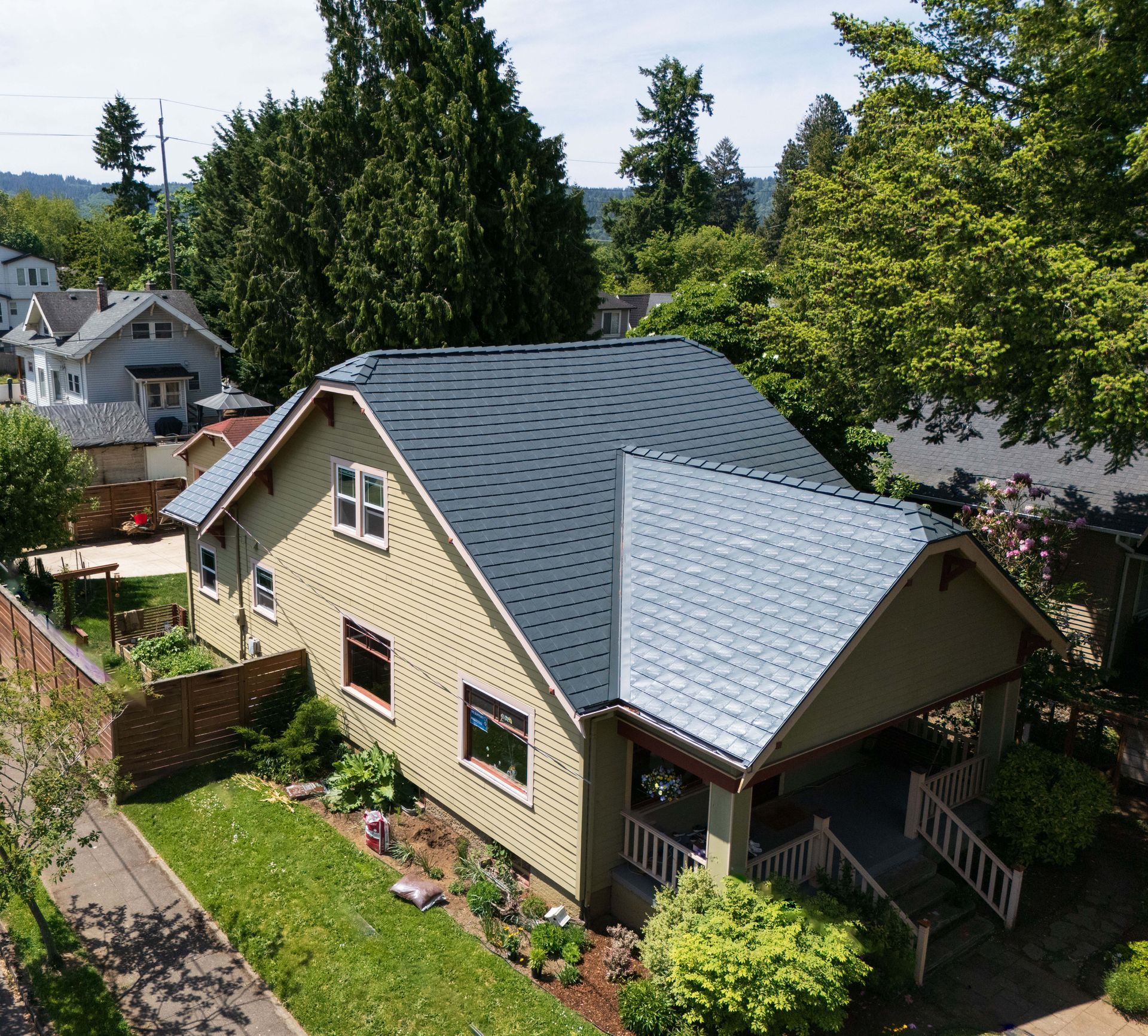Aerial view of a craftsman-style home in the University Park neighborhood of Portland, Oregon, featuring a Deep Charcoal Interlock Slate Roof made from heavy-gauge aluminum. Installed by Interlock Metal Roofing, the roof enhances curb appeal while offering long-lasting, fire-resistant protection suited for the Pacific Northwest climate.