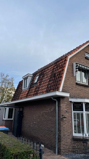 Een bakstenen huis met een rood pannendak en twee ramen.