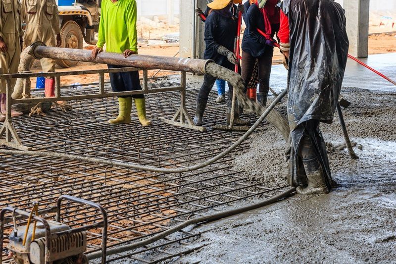 A group of construction workers are pouring concrete on a construction site.