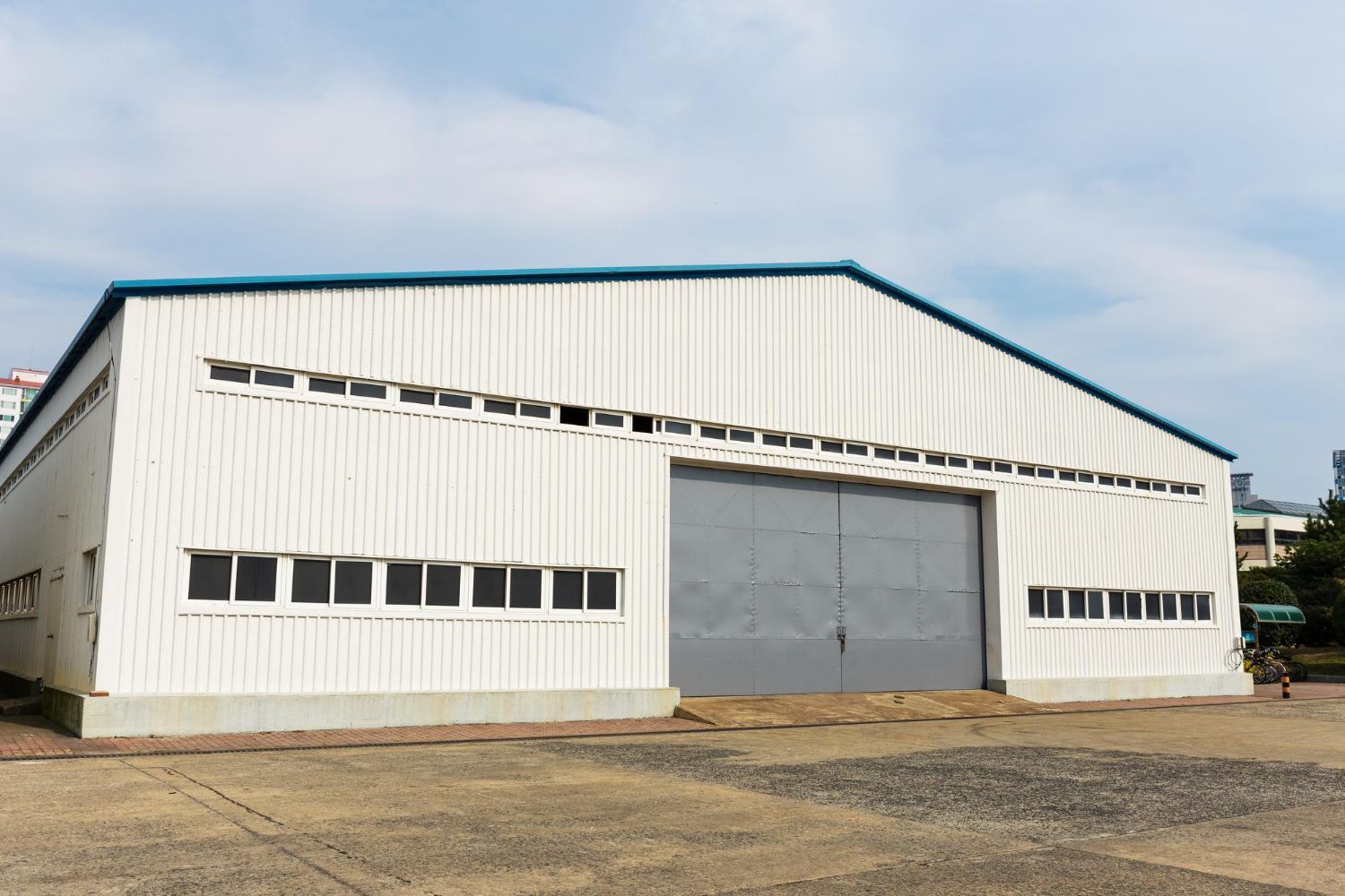 A large white building with a blue roof and a large garage door.