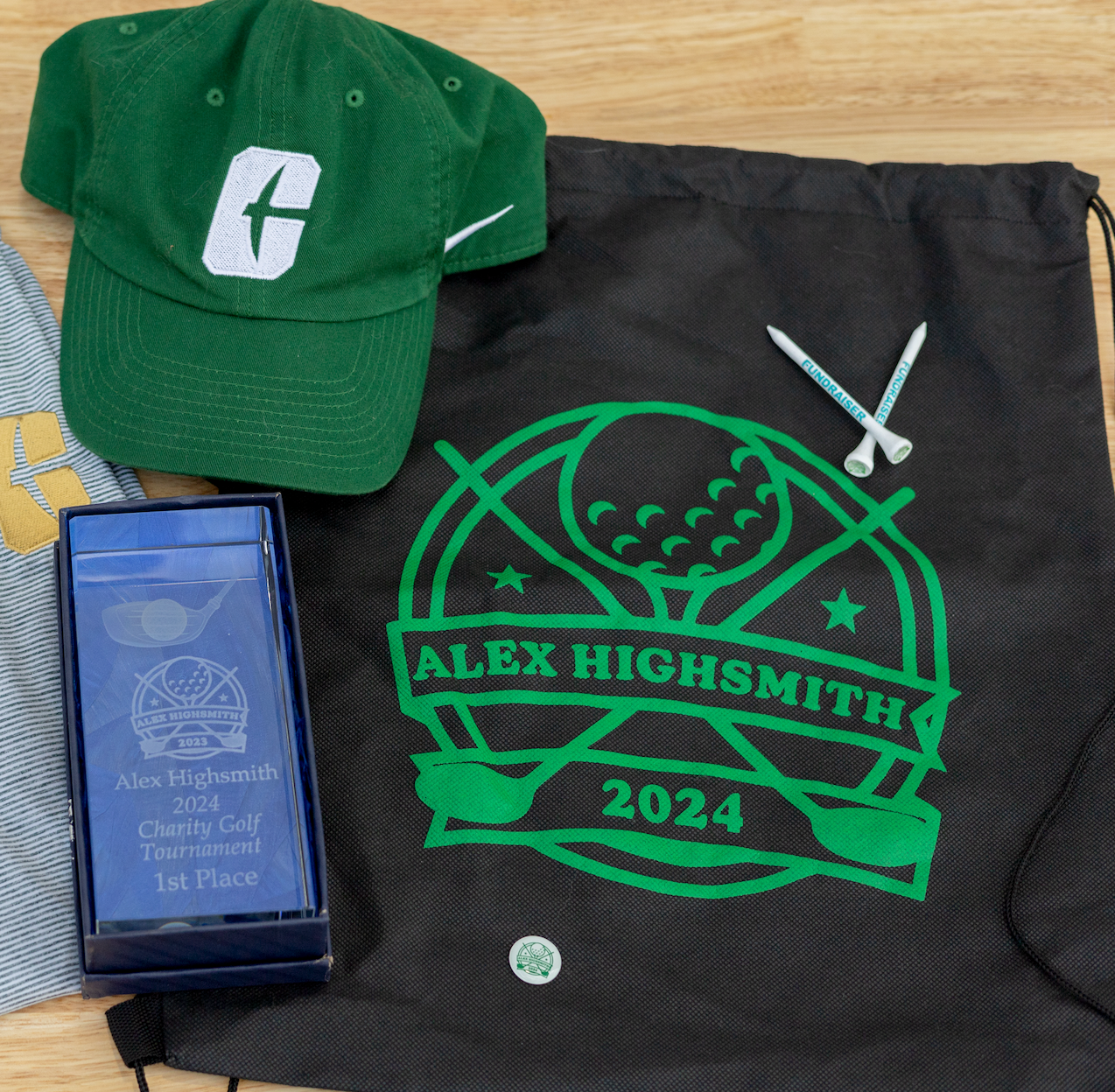 Golf swag: green hat, drawstring bag with logo, award box, and tees.
