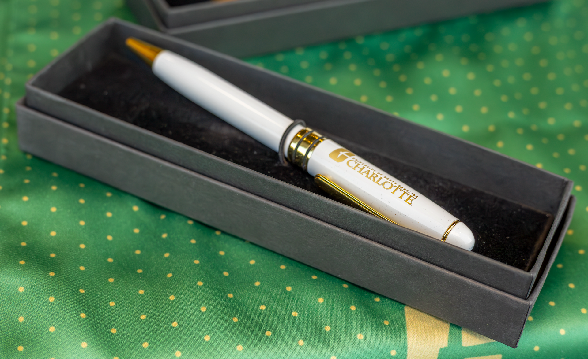 White pen with gold accents in a gray box, with 