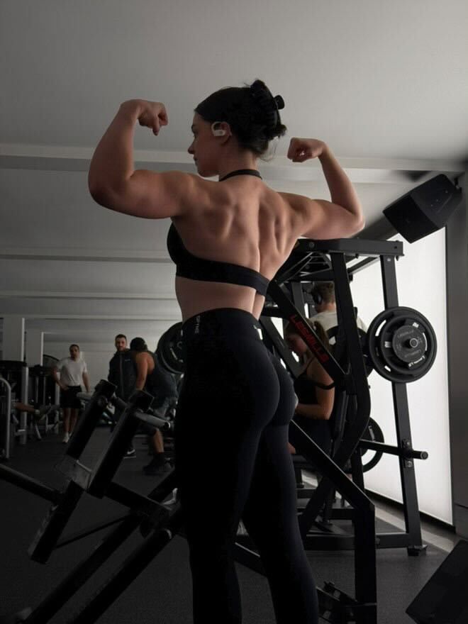 A woman is flexing her muscles in a gym