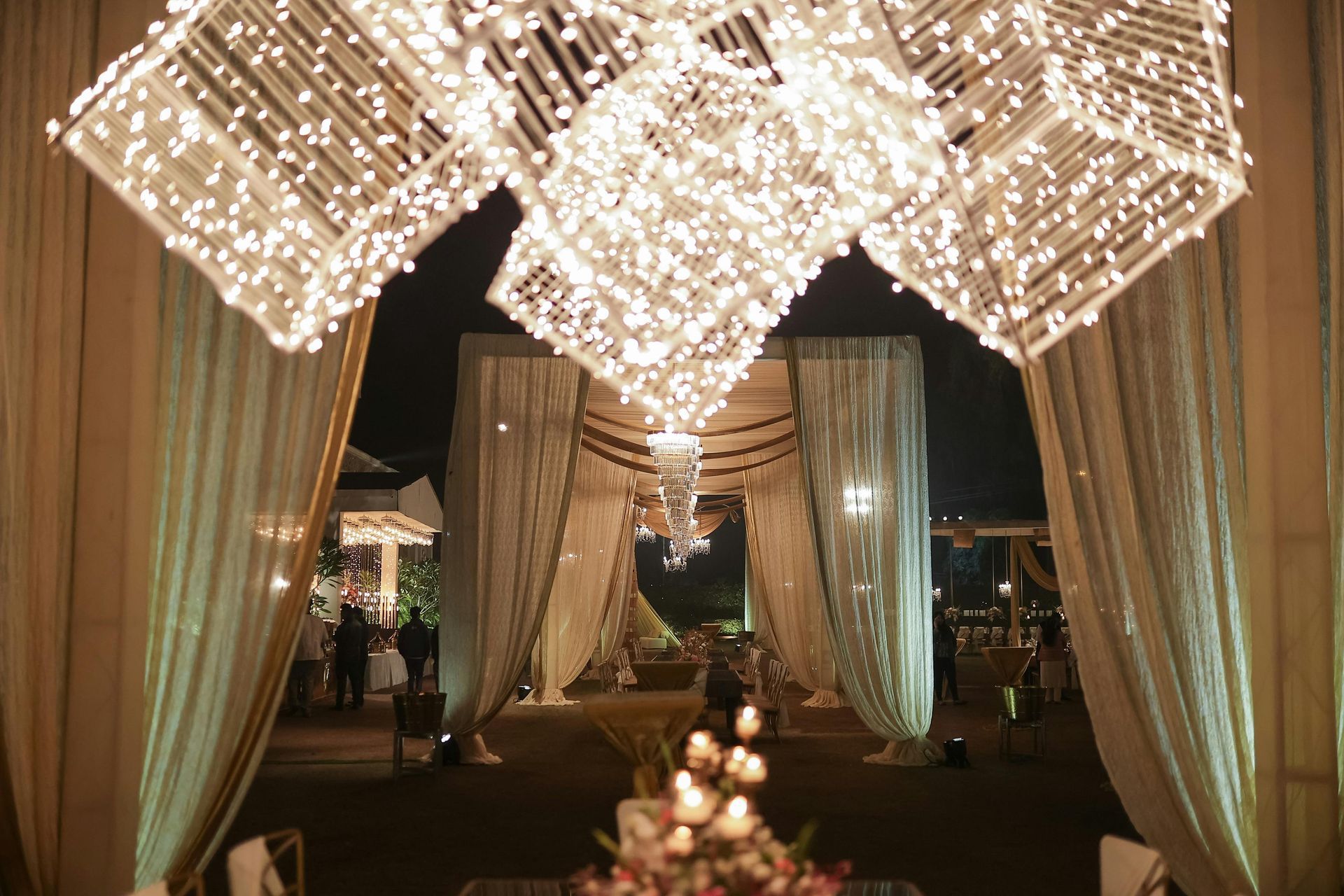 Ornate, illuminated wedding entrance; cream-colored curtains, string lights.