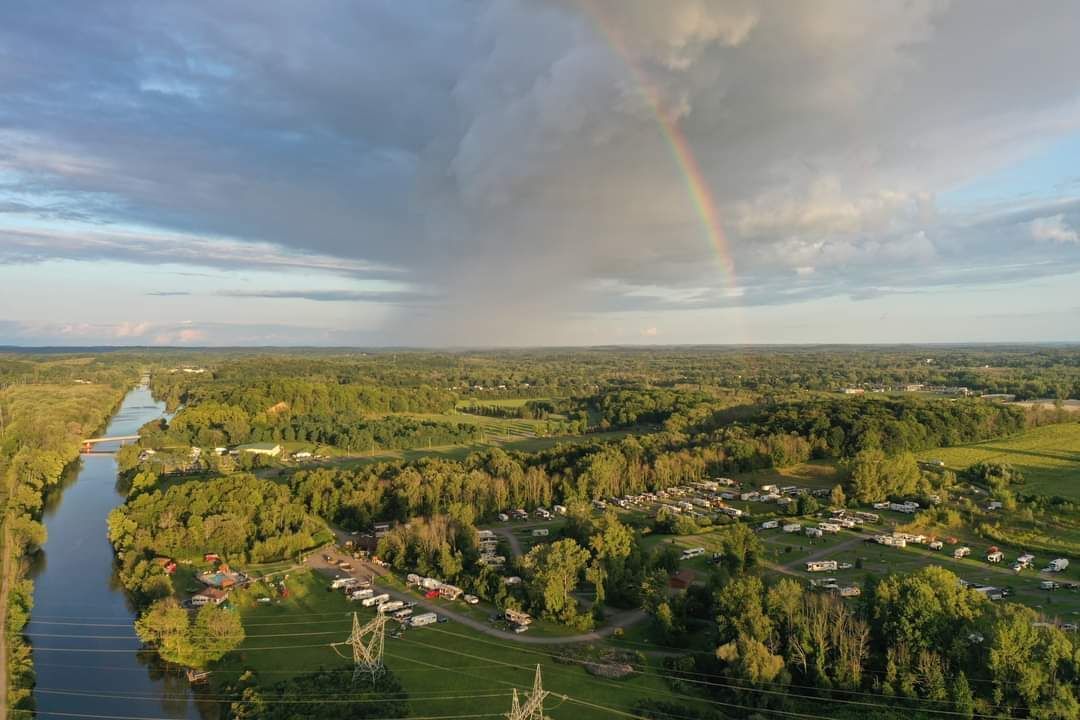 An aerial view of a river with a rainbow in the sky.