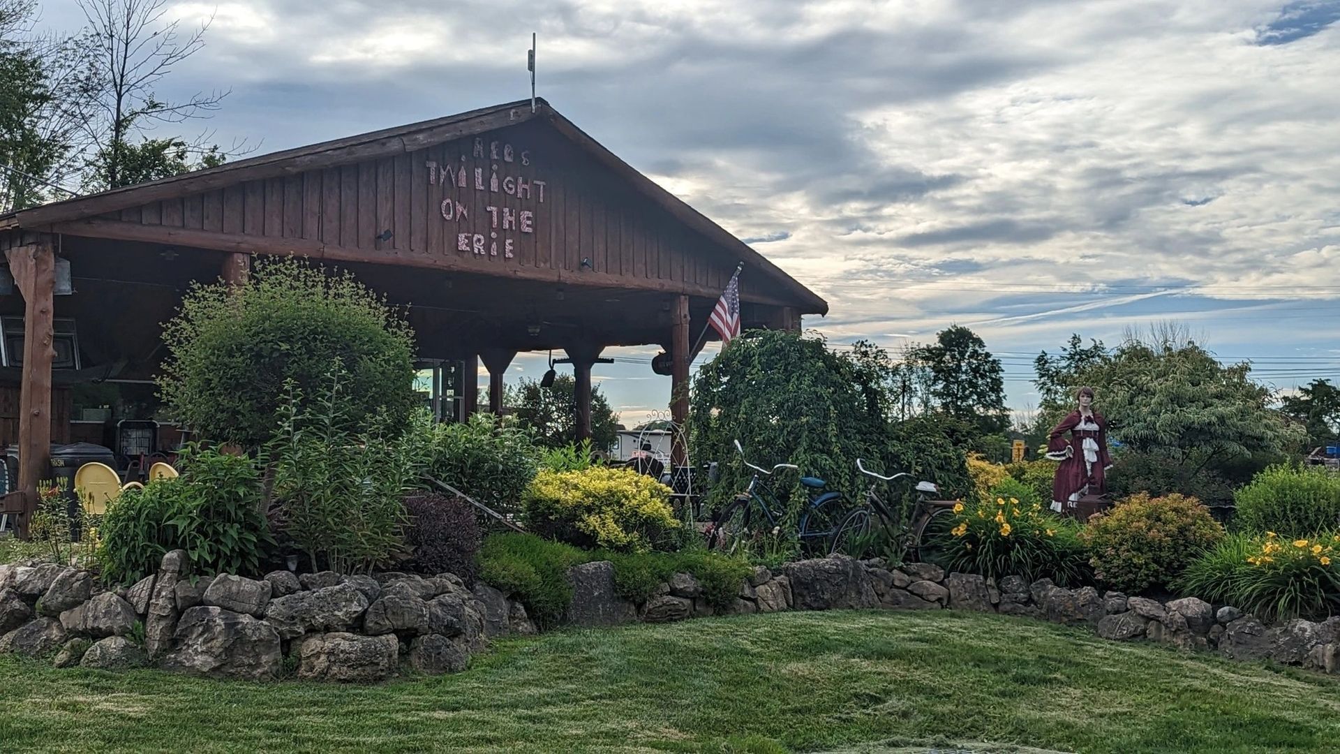 A large wooden building is surrounded by trees and bushes.