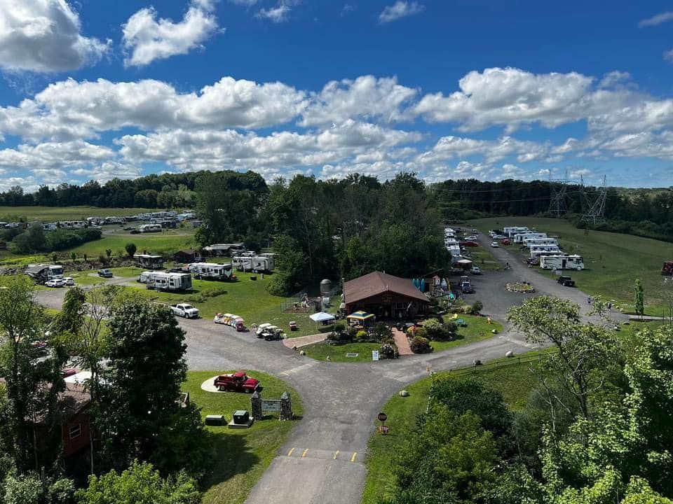 An aerial view of a campground with a lot of rvs parked in the grass.