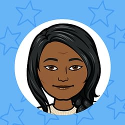 A woman in a white shirt is sitting at a table with a notebook.