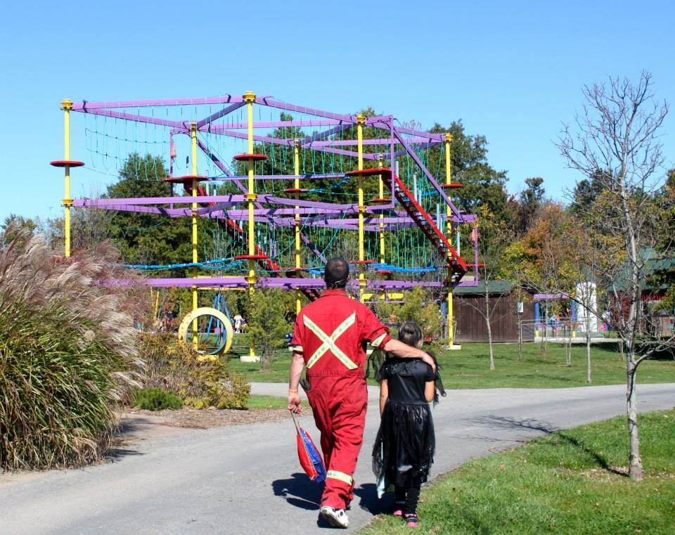 a man in a red jumpsuit is walking with a girl looking at the skyquest obstacle course niagara zoo activities