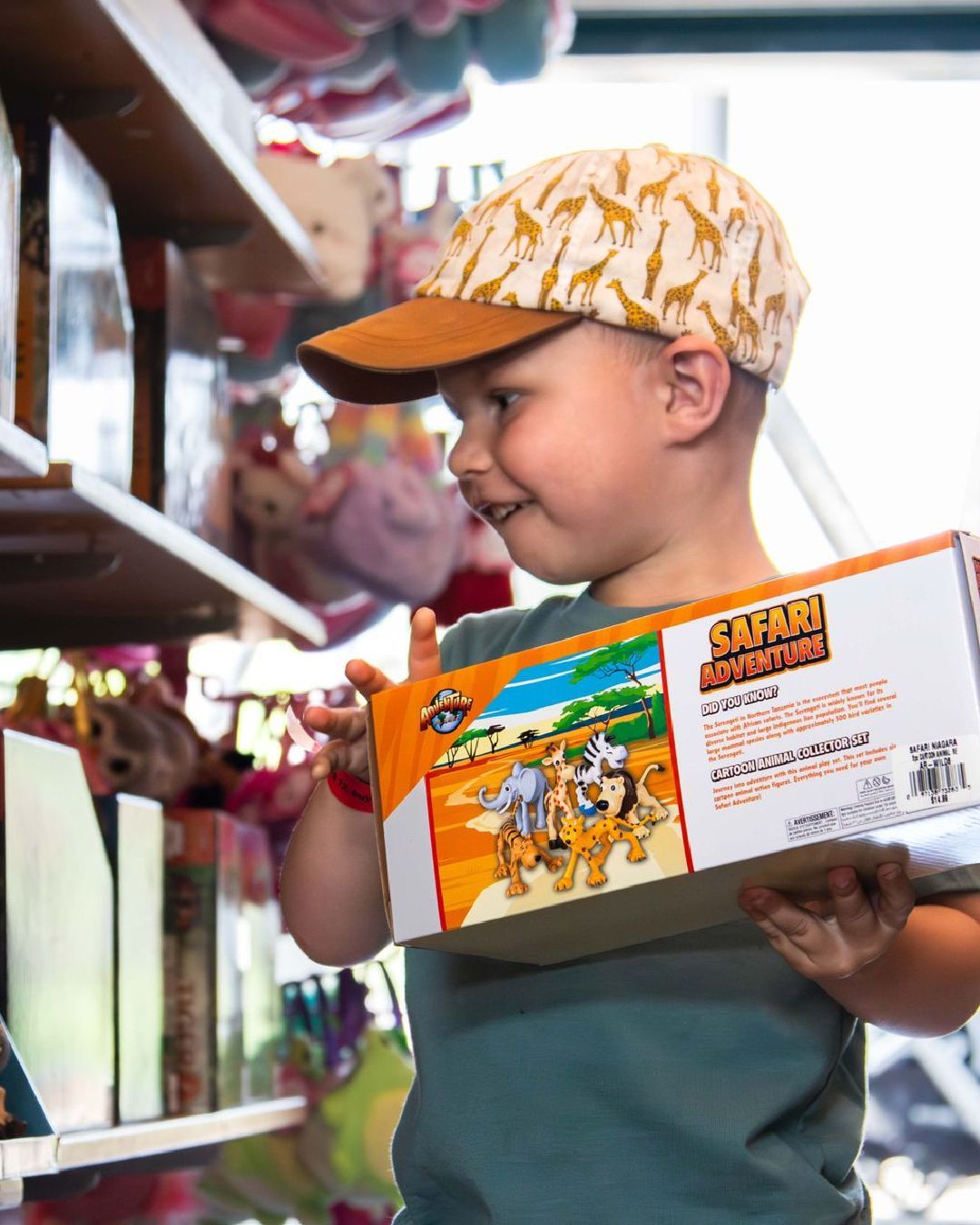 a young boy wearing a safari hat is holding a toy in safari niagara gift shop, a zoo in the niagara region