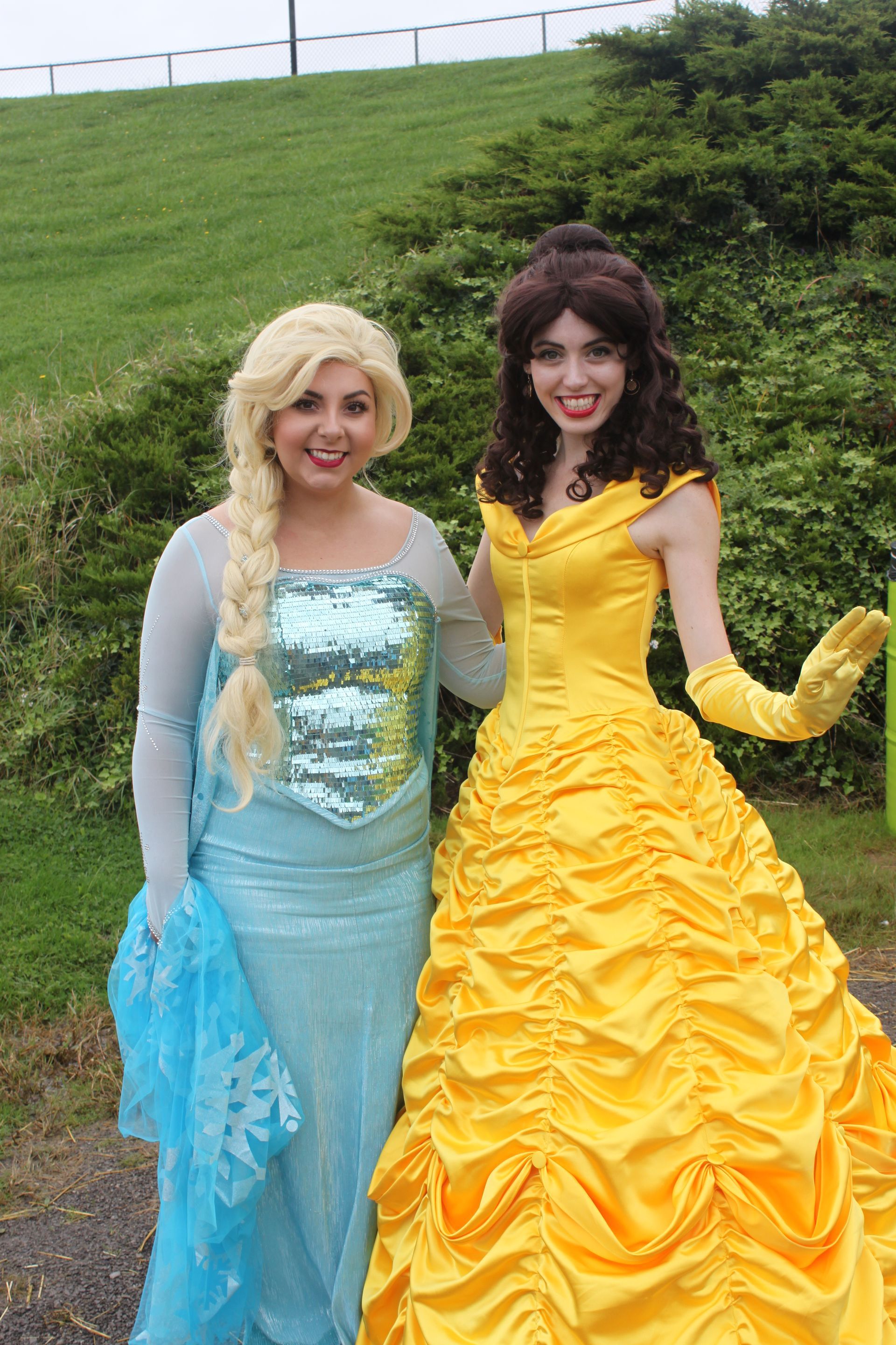 two women dressed as elsa and belle pose for a picture
