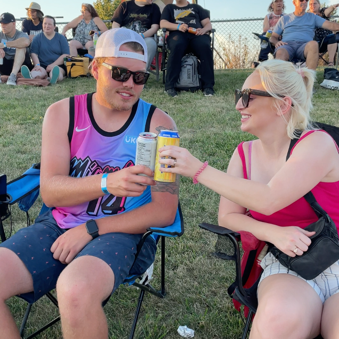 a man and a woman are toasting with cans of beer