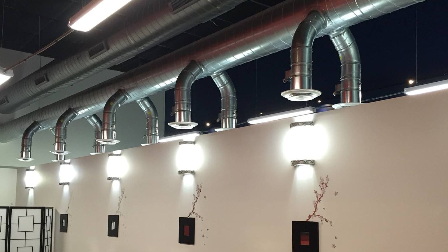 A room with a lot of tables and chairs in it with HVAC ductwork installed by AFA Service