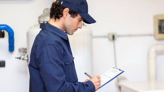 A man in a blue uniform is writing on a clipboard.