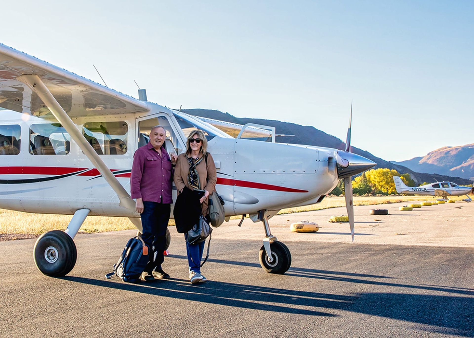 Couple standing in front of an airplane on the tarmac at Canyonlands Field Airport.