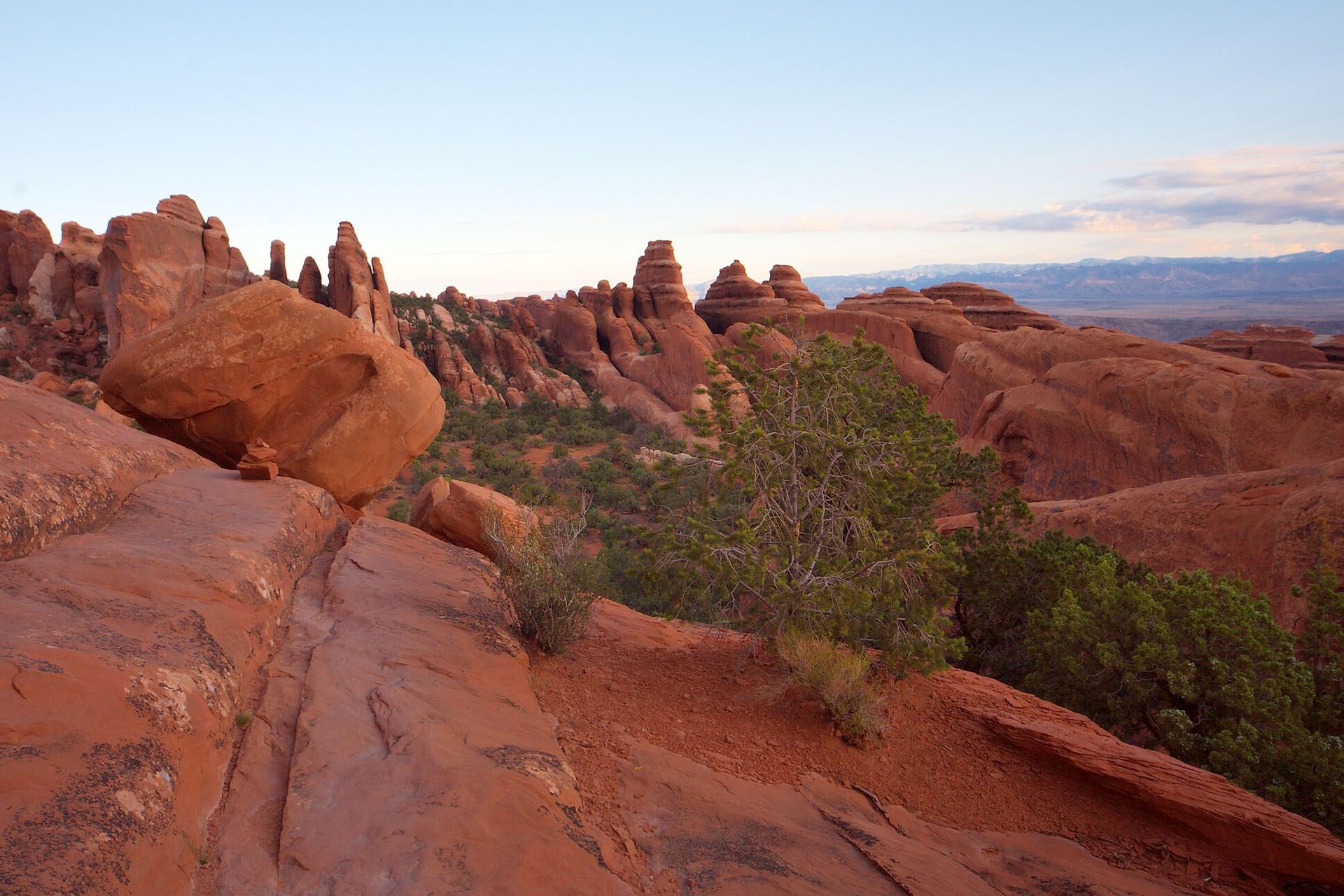 A large rock formation in the middle of a canyon with a cloudy sky in the background.