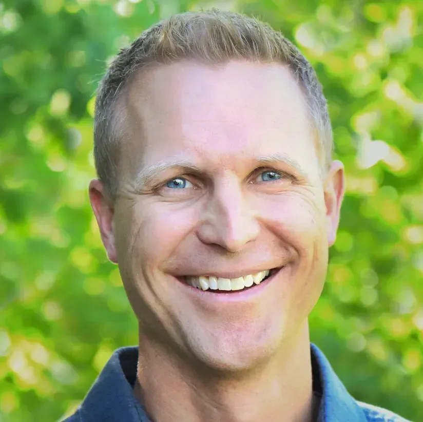Brandon Lake smiling in front of green trees.