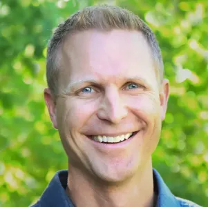 Brandon Lake smiling in front of green trees.