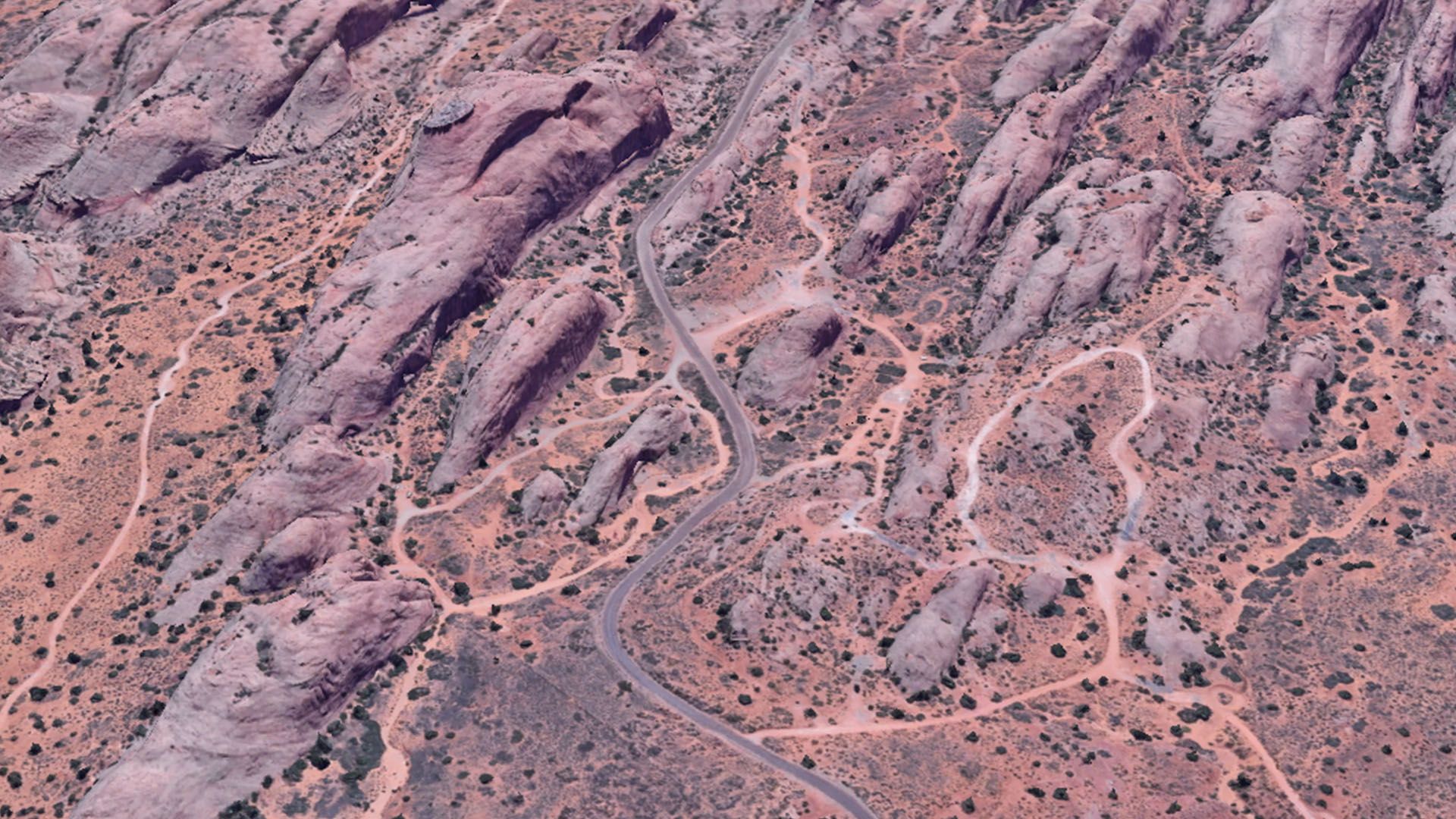 Aerial view of a winding campground loop road through reddish-brown sandstone formations and desert vegetation.