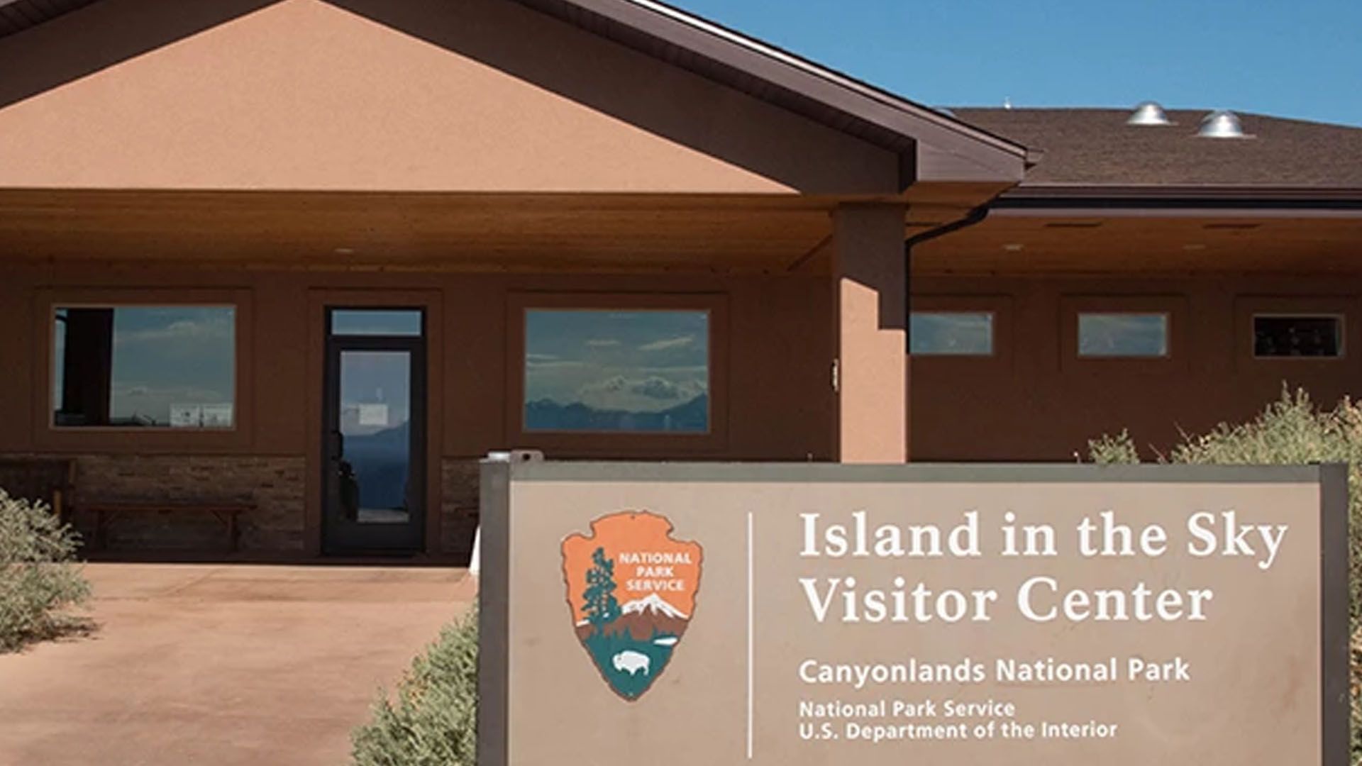 Island in the Sky Visitor Center at Canyonlands National Park, brown building with sign and windows.