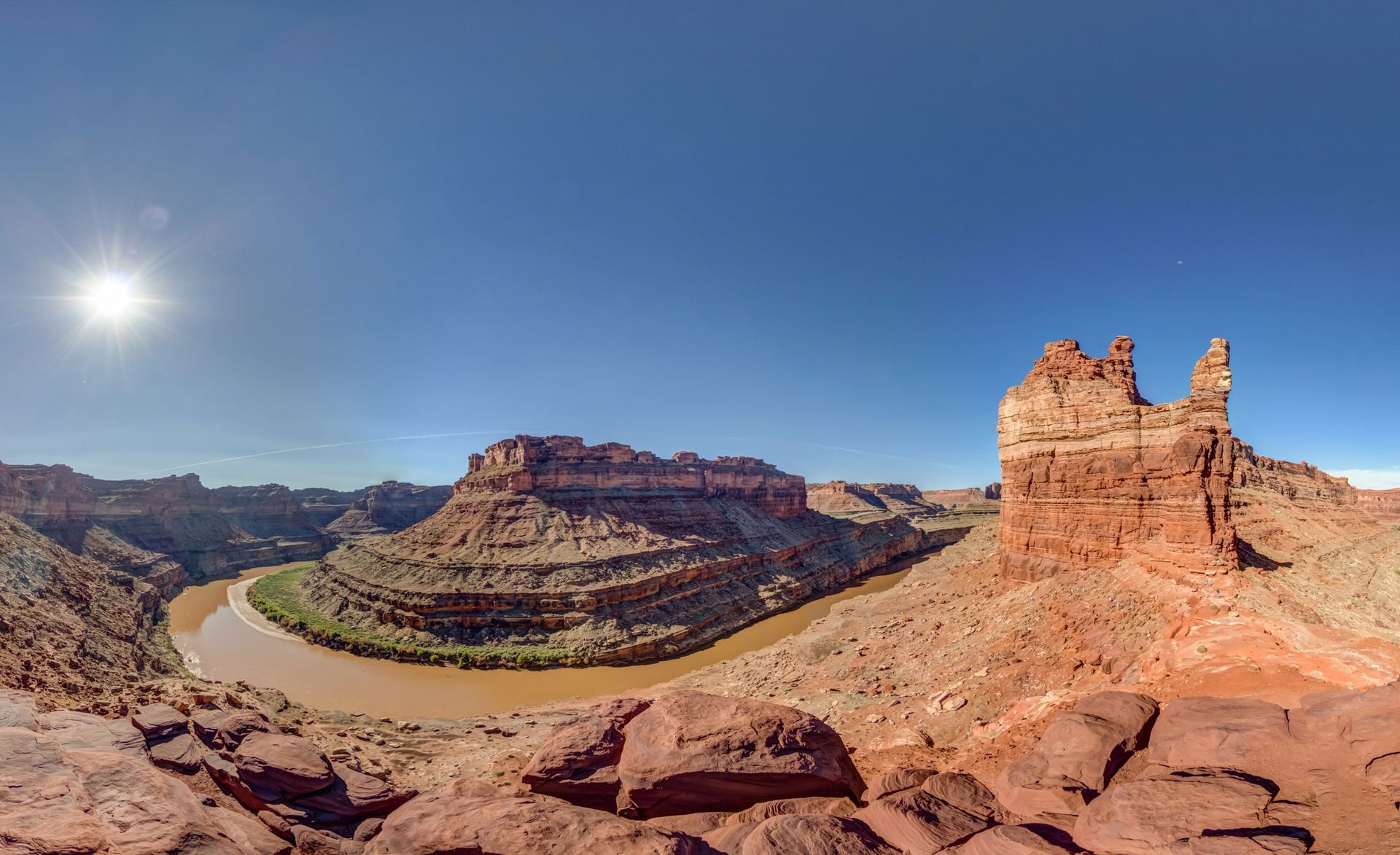 Canyon landscape with a winding river. Red rock formations under a bright blue sky.