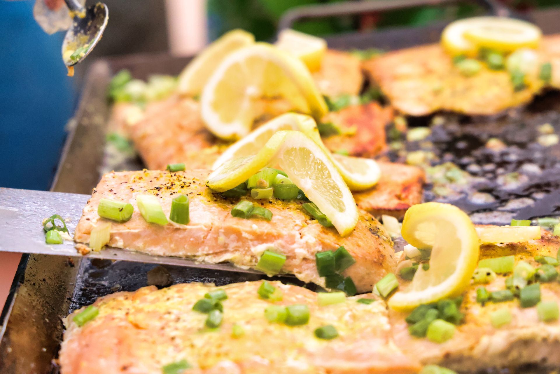 A guide cooks fresh trout on a grill with green onions and lemons.