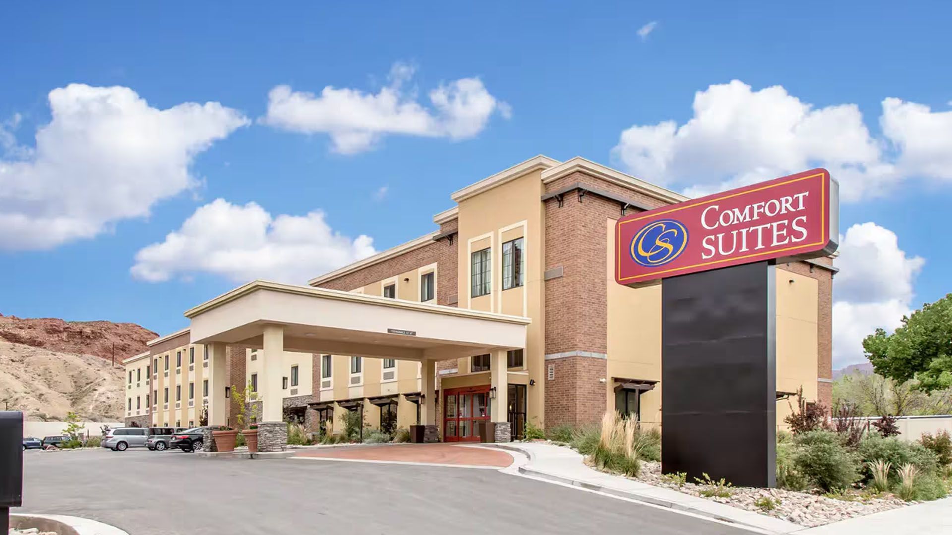 Comfort Suites hotel exterior with sign under blue sky.
