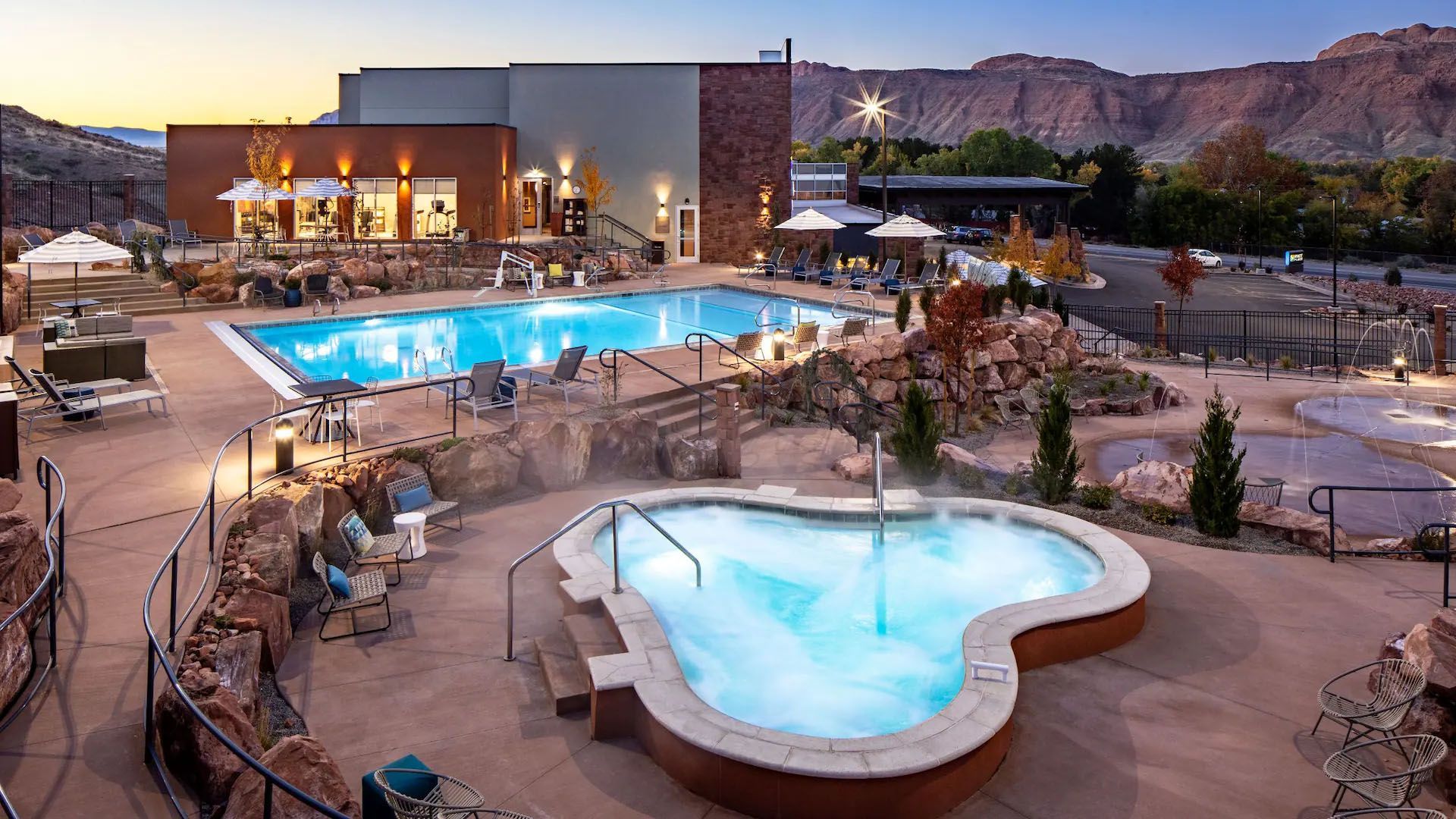 A resort with pools, hot tubs, and landscaping against a desert mountain backdrop.