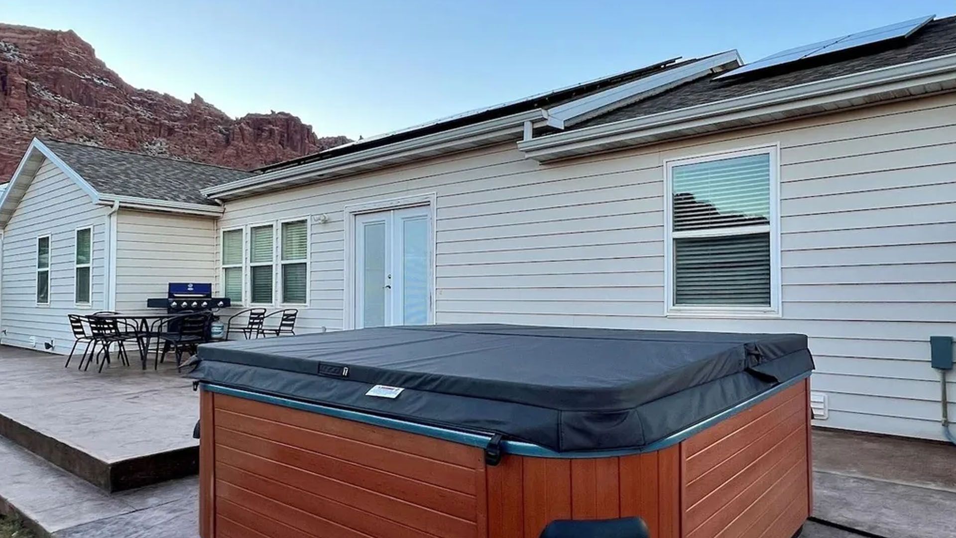 Hot tub on patio with view of house and red rock mountains.
